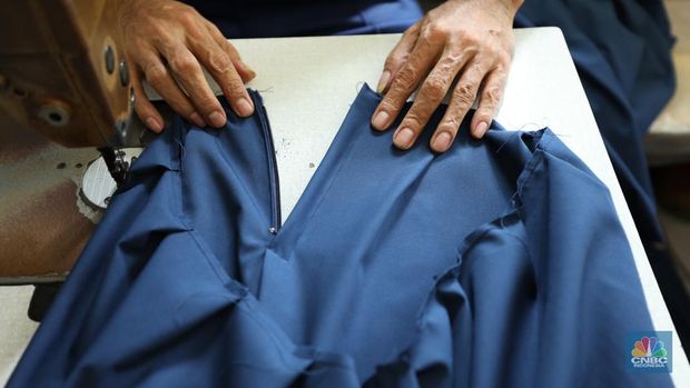 Penjahit menyelesaikan pembuatan baju seragam sekolah di sebuah industri rumahan di kawasan Jakarta, Rabu (26/6/2024).  (CNBC Indonesia/Tri Susilo)
