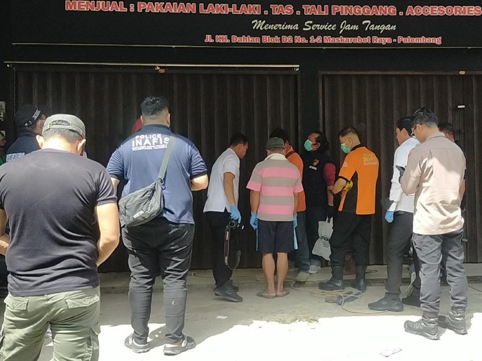 Polisi saat melakukan evakuasi jasad pegawai koperasi yang dikubur di belakang distro Ppalembang