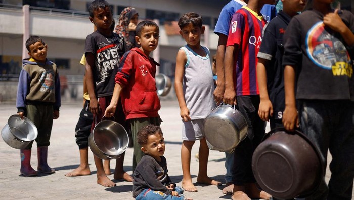 Bencana Kelaparan Kian Nyata, Warga Gaza Kesulitan Dapat Makan dan Air Palestinians gather to receive food cooked by a charity kitchen, amid food scarcity, as Israel-Hamas conflict continues, in Khan Younis in the southern Gaza Strip, June 26, 2024. REUTERS/Mohammed Salem