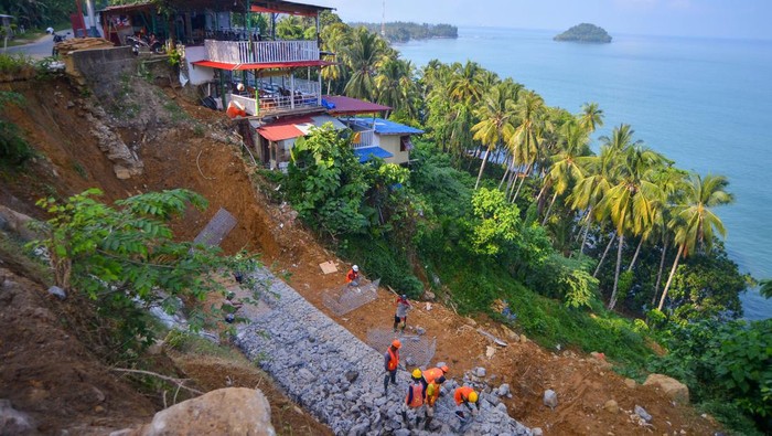 Pekerja memasang batu bronjong di bahu jalan yang longsor di jalan lingkar Nipah - Teluk Bayur, Bukit Gado-gado, Padang, Sumatera Barat, Kamis (27/6/2024). Pemprov Sumbar melakukan perbaikan sejumlah infrastruktur pasca bencana di jalan alternatif yang masuk dalam kawasan wisata terpadu Gunung Padang.  ANTARA FOTO/Iggoy el Fitra/Spt.