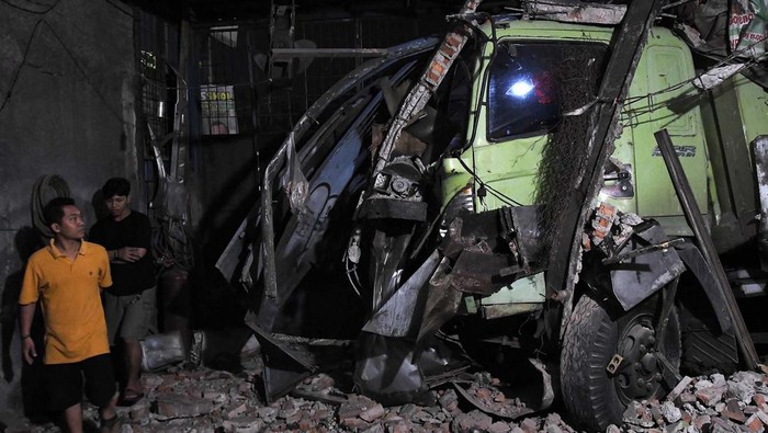 Kendaraan melintas di samping truk yang mengalami kecelakaan di Jalan Sultan Agung, Bekasi, Jawa Barat, Kamis (27/6/2024). Kecelakaan yang melibatkan dua mobil truk kontainer itu mengakibatkan sebuah pagar bengkel las rusak, tidak ada korban jiwa pada kejadian tersebut. ANTARA FOTO/ Fakhri Hermansyah/Spt.