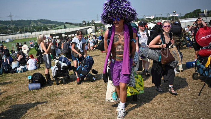 Revellers haul luggage as they arrive at Worthy Farm in Pilton, Somerset for the Glastonbury Festival, Britain, June 26, 2024. REUTERS/Dylan Martinez