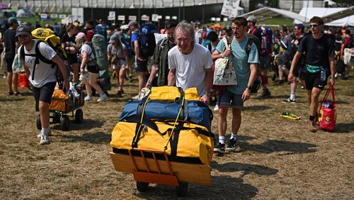 Revellers haul luggage as they arrive at Worthy Farm in Pilton, Somerset for the Glastonbury Festival, Britain, June 26, 2024. REUTERS/Dylan Martinez