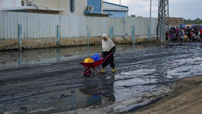 Palestinians gather to fill water jugs near one of the strip's few functioning desalination plants in Deir al-Balah, Gaza Strip, Thursday, June 20, 2024. Israel's war in Gaza has decimated the strip's sanitation system while simultaneously displacing the vast majority of the population, leaving many Palestinians living in tent camps nearby growing piles of garbage. (AP Photo/Abdel Kareem Hana)