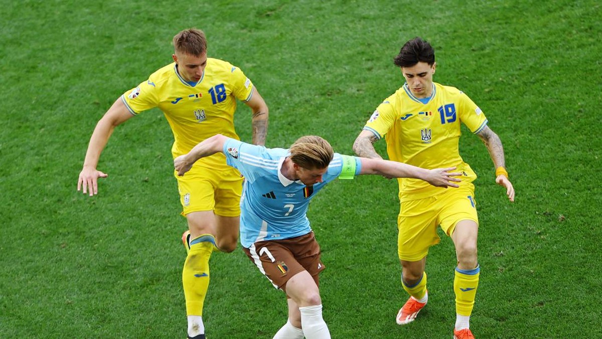 Kevin de Bruyne diapit dua pemain Ukraina pada Euro 2024. (Foto: REUTERS/Leonhard Simon)