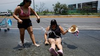 Air yang mengalir ke jalanan dimanfaatkan warga untuk mandi.