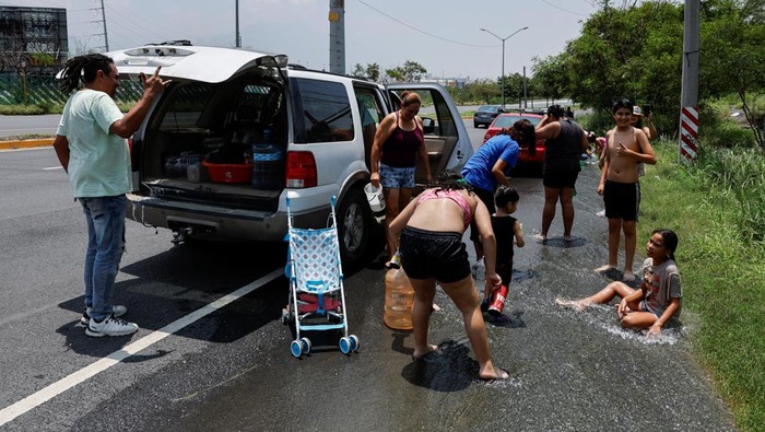 People collect water from the runoff of the Topo Chico mountain, after drinking water pipes were damaged by tropical storm Alberto, in San Pedro Garza Garcia, Mexico June 26, 2024. REUTERS/Daniel Becerril