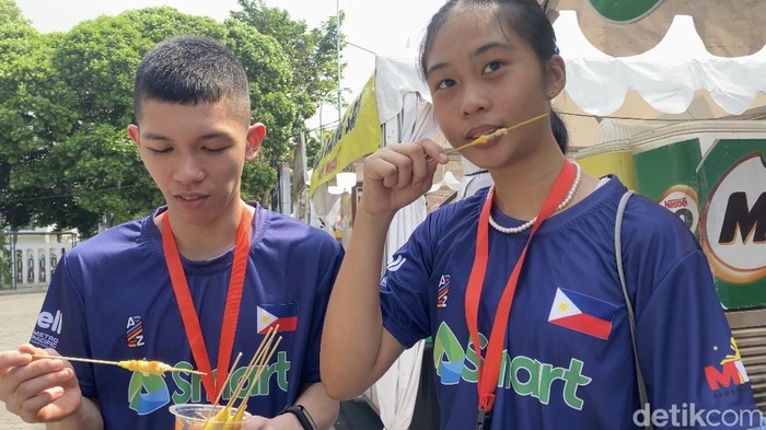 Pebulutangkis Filipina, Zeth Quiambao dan Fuentespina Christei Rei makan telur gulung di sela event Badminton Asia Junior Championships 2024 di GOR Among Rogo Jogja, Jumat (28/6/2024).