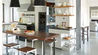 Dapur ini didominasi elemen logam dan kayu di seluruh ruang, meja makan, dan bangku konter. Garis-garis yang tegas dan dekorasi minimalis memberikan daya tarik modern. Foto: KRITSADA PANICHGUL via Better Homes & Gardens