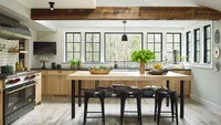 Aksen hitam dan warna kayu memberi estetika industrial pada ruang ini. Oven ganda yang mewah dengan pintu hitam kontras dan lantai kayu yang sudah usang, serta meja dapur hitam berada di atas lemari berwarna cokelat. Foto: TRIO GIOVAN via Better Homes & Gardens
