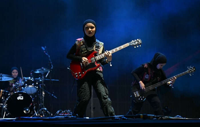 BRITAIN-MUSIC-FESTIVAL Indonesian rock band, Voice of Baceprot, comprised of Firda Marsya Kurnia (C), Widi Rahmawati (R) and drummer Euis Siti Aisyah perform on the Woodsies stage on the third day of the Glastonbury festival at Worthy Farm in the village of Pilton in Somerset, southwest England, on June 28, 2024. The festival takes place from June 26 to June 30. (Photo by Oli SCARFF / AFP)