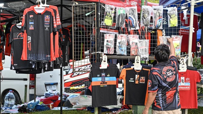 Seorang pedagang memajang jersey serta pernak-pernik bertemakan MXGP yang dijualnya di areal parkiran sirkuit Motocross Grand Prix (MXGP) di bekas Bandara Selaparang, Mataram, NTB, Sabtu (29/6/2024). Pedagang pernak-pernik berupa kaos, jersey dan topi bertemakan MXGP tersebut datang dari Bandung dan menjual dagangannya mulai harga Rp60 ribu hingga Rp200 ribu.ANTARA FOTO/Ahmad Subaidi/foc.