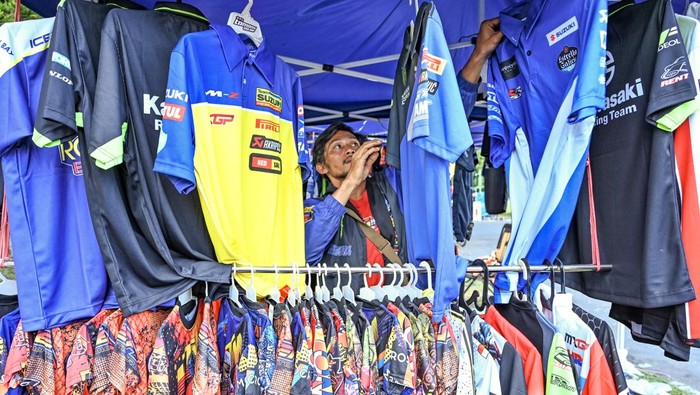 Seorang pedagang memajang jersey serta pernak-pernik bertemakan MXGP yang dijualnya di areal parkiran sirkuit Motocross Grand Prix (MXGP) di bekas Bandara Selaparang, Mataram, NTB, Sabtu (29/6/2024). Pedagang pernak-pernik berupa kaos, jersey dan topi bertemakan MXGP tersebut datang dari Bandung dan menjual dagangannya mulai harga Rp60 ribu hingga Rp200 ribu.ANTARA FOTO/Ahmad Subaidi/foc.