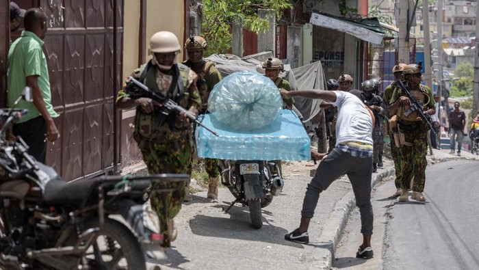 Potret Patroli Keamanan di Haiti Perangi Geng Bersenjata Kenyan Police guard the site where one of the armoured vehicles used by the Kenyan police and Haitian National police SWAT units to patrol broke down on a steep hill while patrolling through a neighborhood, after the arrival of the first contingent of Kenyan police as part of a peacekeeping mission, in Port-au-Prince, Haiti June 28, 2024. REUTERS/Ricardo Arduengo