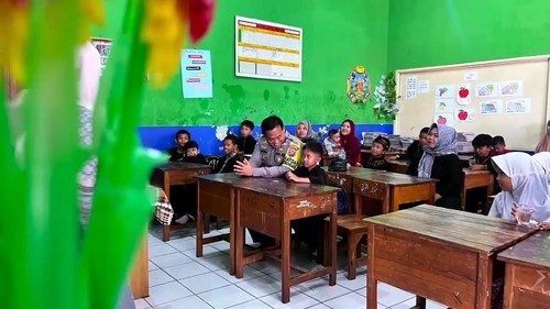 Seorang anak bernama Ilham Ramadhan (8) meminta polisi menemaninya saat pembagian rapor.