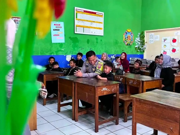 Seorang anak bernama Ilham Ramadhan (8) meminta polisi menemaninya saat pembagian rapor.