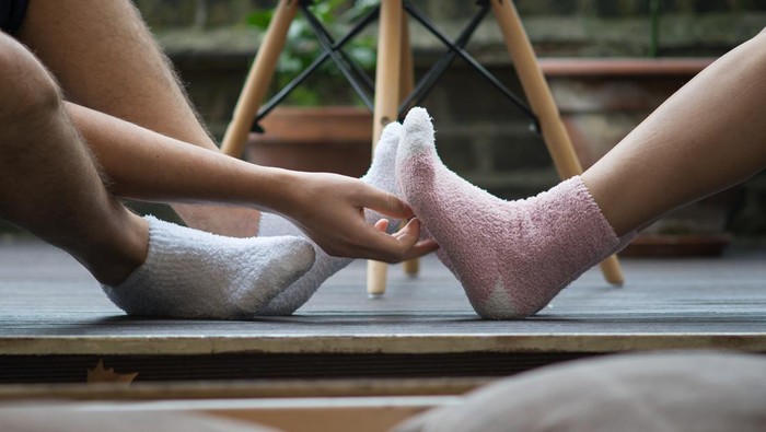 Man and womans feet wearing cosy socks, one tickling the other