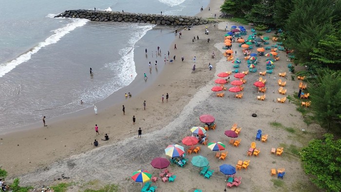 Foto udara sejumlah pengunjung memadati kawasan Pantai Padang, Sumatera Barat, Minggu (30/6/2024). Destinasi wisata pantai Padang menjadi pilihan bagi warga dan pengunjung menikmati masa libur panjang sekolah, karena akses utama ke Bukittinggi dan sekitarnya belum bisa dilewati sebab masih dalam perbaikan pascabanjir bandang bulan lalu. ANTARA FOTO/Iggoy el Fitra/aww.