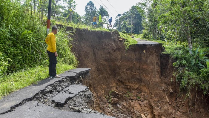 Warga berdiri di dekat jalan longsor di Desa Puspamukti, Kabupaten Tasikmalaya, Jawa Barat, Minggu (30/6/2024). Intensitas hujan yang tinggi mengakibatkan jalan penghubung antarkampung longsor sehingga menyebabkan akses jalan di Kampung Parung, Kiarabongkok, Salawi, Kecamatan Cilaglontang, terisolir karena tidak bisa dilalui. ANTARA FOTO/Adeng Bustomi/aww.