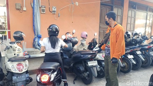Putu Aditya Mahesa Putra (19) melayani pengunjung PKB yang memarkirkan motor, Minggu (30/6/2024). Mahesa adalah satu dari sekian warga yang mencari cuan dengan menyewakan lahan parkir saat PKB. (Ni Made Lastri Karsiani Putri)