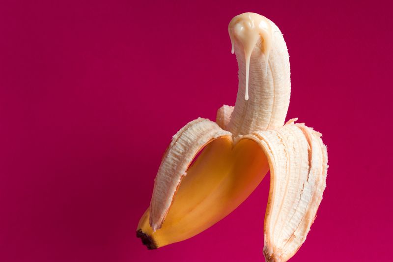 banana and drops of condensed milk on a vivid pink background