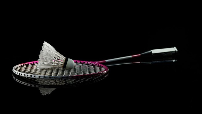 Badminton racket. Professional sport equipment isolated on black studio background. Concept of sport, leadership, competition, healthy lifestyle in motion and action, training. Close up, copyspace.