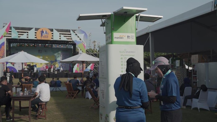 Peserta Mandiri Jogja Marathon 2024 melakukan charging handphone melalui terminal listrik tenaga surya yang disediakan SUN Energy, Minggu (30/6/2024).
