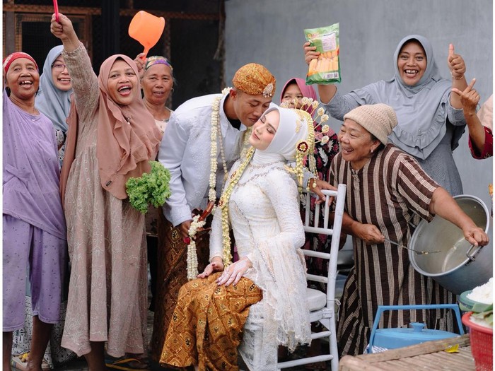 Foto pasangan Andy dan Yunda yang mengabadikan momen bersama ibu-ibu yang bertugas di dapur dan berjasa di hari pernikahannya. Unggahan tersebut langsung viral di media sosial