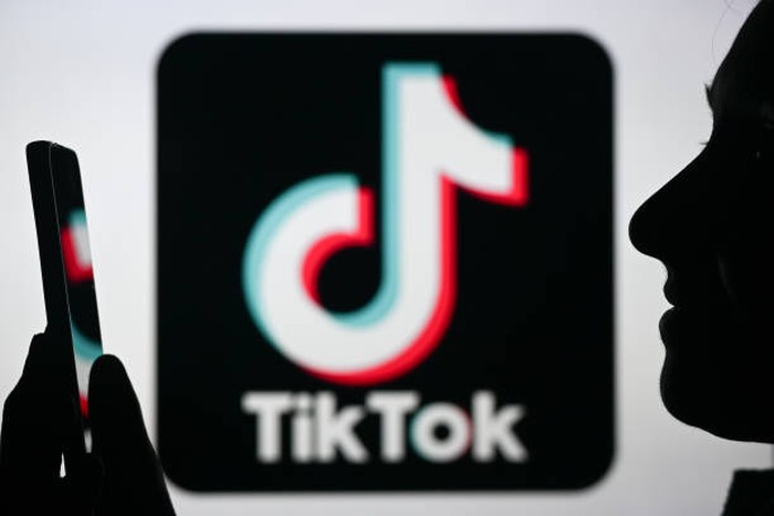 EDMONTON, CANADA - APRIL 28:
An image of a woman holding a cell phone in front of the Tik Tok logo displayed on a computer screen, on April 29, 2024, in Edmonton, Canada. (Photo by Artur Widak/NurPhoto via Getty Images)