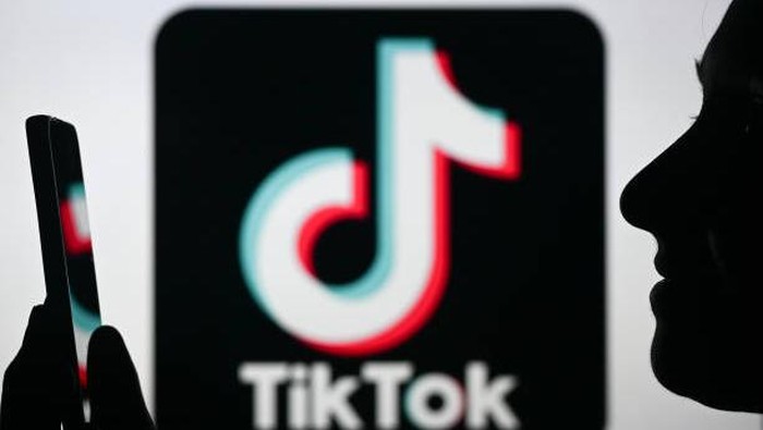 Ilustrasi seseorang sedang melihat konten video TikTok. EDMONTON, CANADA - APRIL 28:
An image of a woman holding a cell phone in front of the Tik Tok logo displayed on a computer screen, on April 29, 2024, in Edmonton, Canada. (Photo by Artur Widak/NurPhoto via Getty Images)