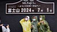 Pengunjung berpose untuk foto pada hari pertama musim pendakian di Jalur Fuji Yoshidaguchi (Rute Yoshida) di stasiun kelima lereng Gunung Fuji, di Fujiyoshida, Prefektur Yamanashi, Jepang, Senin (1/7/2024).