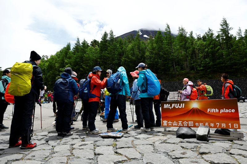 Visitors pose for a photo on the first day of climbing season at Fuji Yoshidaguchi Trail (Yoshida Route) at the fifth station of the slopes of Mount Fuji, in Fujiyoshida, Yamanashi Prefecture, Japan July 1, 2024. REUTERS/Issei Kato