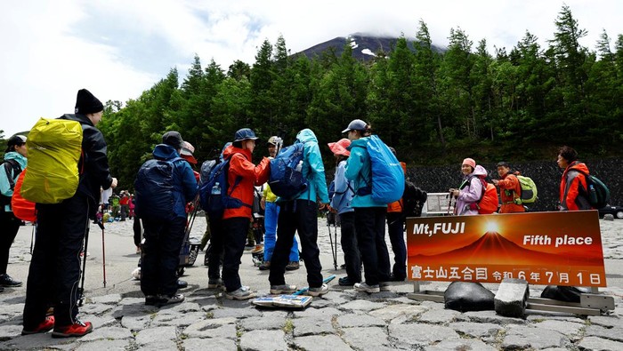 Imbas Lonjakan Turis, Mendaki Gunung Fuji Kini Dipatok Tarif Visitors pose for a photo on the first day of climbing season at Fuji Yoshidaguchi Trail (Yoshida Route) at the fifth station of the slopes of Mount Fuji, in Fujiyoshida, Yamanashi Prefecture, Japan July 1, 2024. REUTERS/Issei Kato