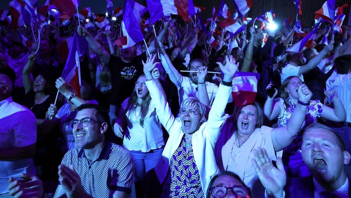 Kubu Macron Tumbang di Putaran Pertama Pemilihan Parlemen Prancis Supporters of Marine Le Pen, French far-right leader and far-right Rassemblement National (National Rally - RN) party candidate, celebrate after partial results in the first round of the early French parliamentary elections, in Henin-Beaumont, France, June 30, 2024. REUTERS/Yves Herman