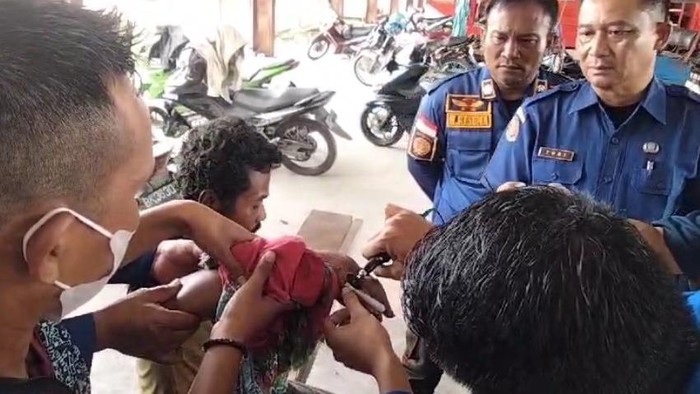 Petugas Damkar saat berusaha melepaskan cincin dan gelang dari tangan pria ODGJ di Asahan. (Dok. Istimewa)