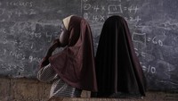 Siswa perempuan berdiri di depan kelas untuk belajar matematika.