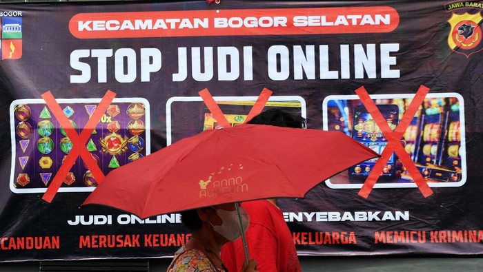 Warga berjalan di depan spanduk sosialisasi larangan judi online di Kantor Kecamatan Bogor Selatan, Kota Bogor, Jawa Barat, Senin (1/7/2024). Spanduk tersebut dipasang di sejumlah titik jalan dan kelurahan di wilayah Kecamatan Bogor Selatan karena berdasarkan data Pusat Pelaporan dan Analisis Transaksi Keuangan (PPATK) menyebutkan bahwa di kecamatan tersebut tercatat menjadi wilayah dengan nilai total transaksi judi online paling tinggi di Indonesia dengan pelaku judi online mencapai 3.720 orang dan perputaran uang sebanyak Rp349 miliar. ANTARA FOTO/Arif Firmansyah/YU