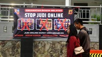 Warga melintas di depan spanduk sosialisasi larangan judi online di Kantor Kecamatan Bogor Selatan, Kota Bogor, Jawa Barat, Senin (1/7/2024).