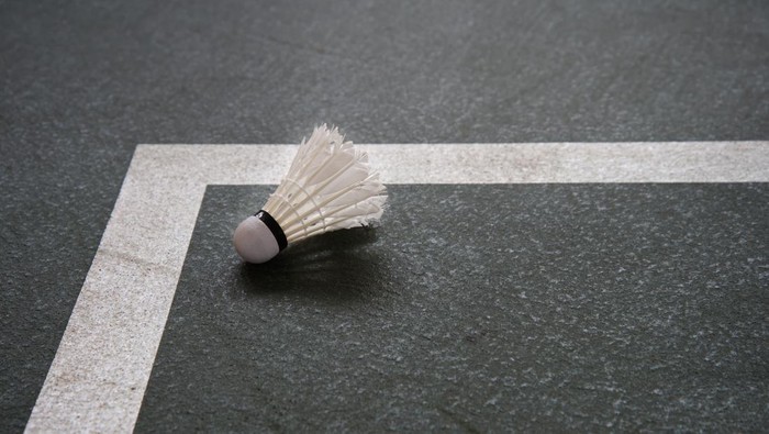 obsolate white shuttlecock for badminton sport game on  corner of indoor court  gymnasium background