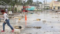 Seorang wanita berjalan melalui jalan yang dipenuhi puing-puing di lingkungan Hastings setelah Badai Beryl melanda Bridgetown, Barbados, Senin (1/7/2024). (REUTERS/Nigel R Browne)  