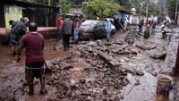Warga membersihkan lumpur dan batu dari jalan setelah hujan lebat akibat Badai Chris menyebabkan tanah longsor, di Huiloapan de Cuauhtemoc.