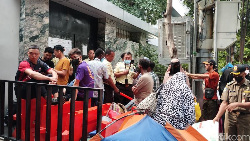 Para pencari suaka dari luar negeri melihat tenda-tendanya digusur Satpol PP, di belakang kantor UNHCR Indonesia, Jaksel, 2 Juli 2024. (Maulana Ilhami Fawdi/detikcom)