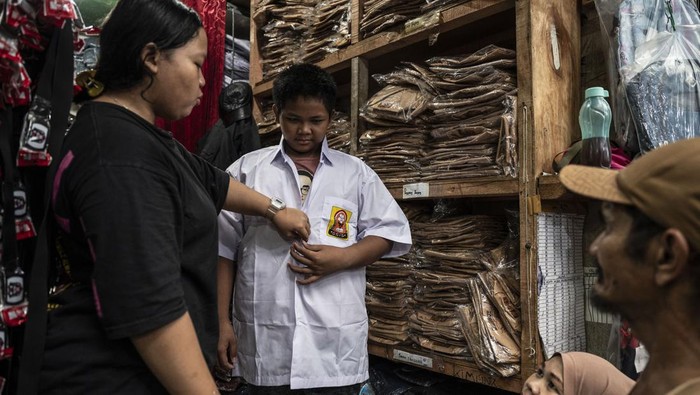 Penjual Seragam Sekolah Diserbu Jelang Tahun Ajaran Baru Pedagang (kiri) membantu seorang anak saat mencoba seragam sekolah di Pasar Jatinegara, Jakarta, Selasa (2/7/2024). Menurut pedagang menjelang tahun ajaran baru 2024/2025 yang akan dimulai pada Senin (8/7), penjualan seragam sekolah yang dijual mulai Rp75 ribu-Rp200 ribu itu mengalami peningkatan hingga lima kali lipat dibanding hari biasa. ANTARA FOTO/Aprillio Akbar/nym.