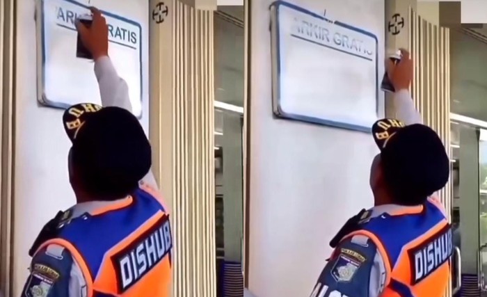 Petugas Dishub hapus tulisan parkir gratis.