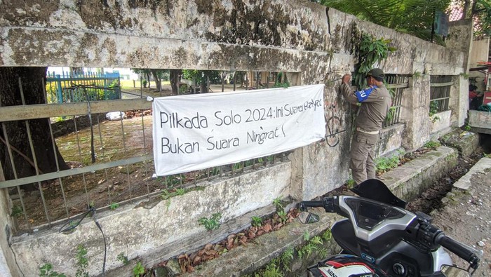 Satpol PP Kota Solo saat mencabut spanduk yang bernada provokatif, Selasa (2/7/2024).