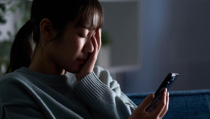 A depressed woman looking at her smartphone