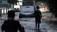 Pengendara mobil dan motor menerobos banjir di lokasi.