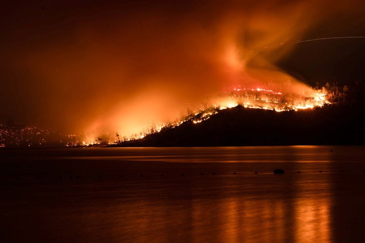 Smoke and flames rise near a house as firefighters battle the Thompson wildfire in a canyon near Oroville, California, U.S., July 2, 2024. REUTERS/Carlos Barria