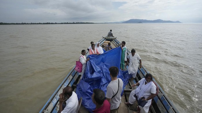 25-year-old Jahanara Khatoon, who is at full-term pregnancy, lies in pain with onset of labour as health officers hold a tarpaulin to give her cover, over the River Brahmaputra, in the northeastern Indian state of Assam, Wednesday, July 3, 2024. (AP Photo/Anupam Nath)