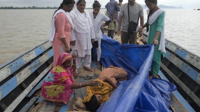 25-year-old Jahanara Khatoon, who is at full-term pregnancy, lies in pain with onset of labour as health officers hold a tarpaulin to give her cover, over the River Brahmaputra, in the northeastern Indian state of Assam, Wednesday, July 3, 2024. (AP Photo/Anupam Nath)